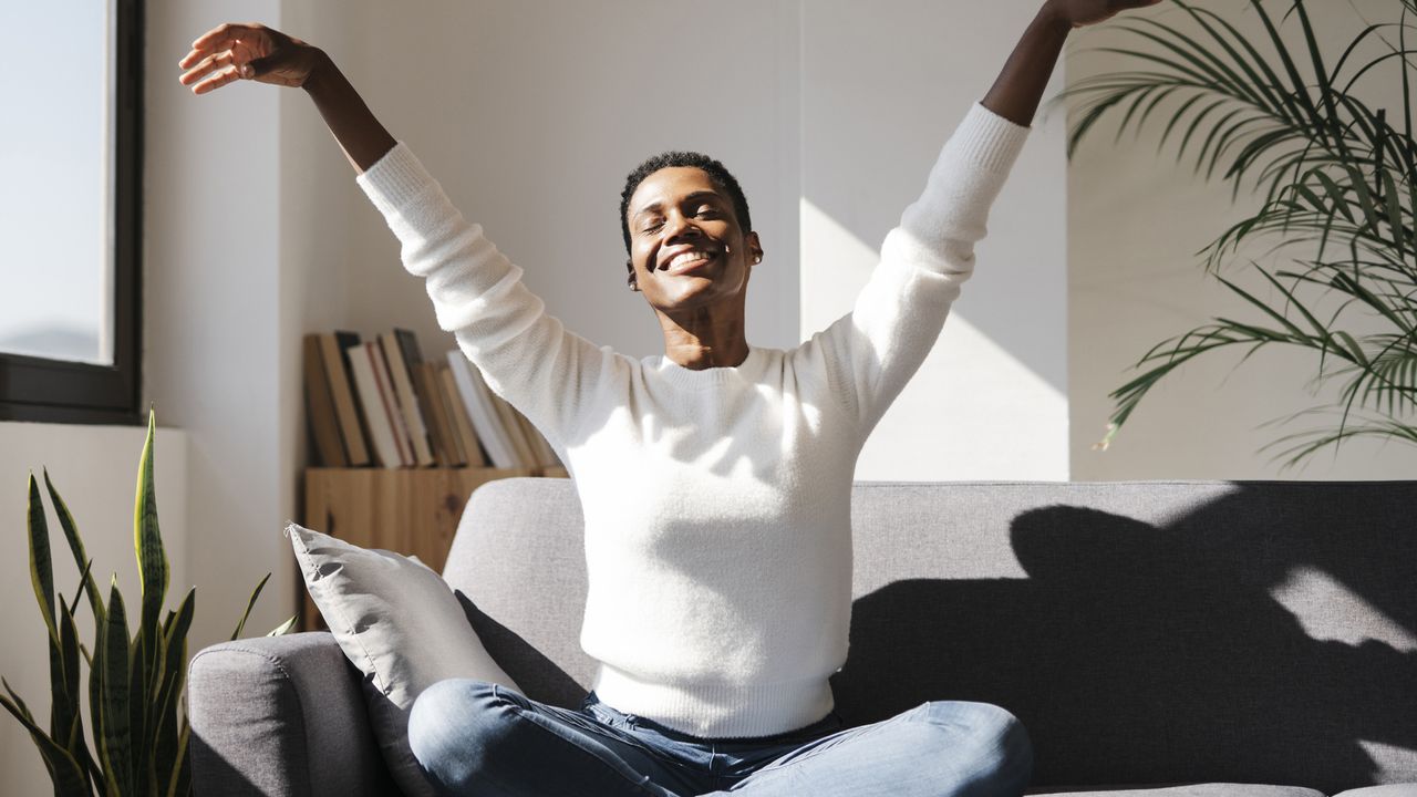 Woman stretching up arms on the couch