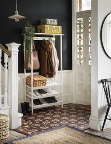 hallway showing white storage unit for shoes and coat, tiled floor black walls