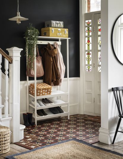 hallway showing white storage unit for shoes and coat, tiled floor black walls