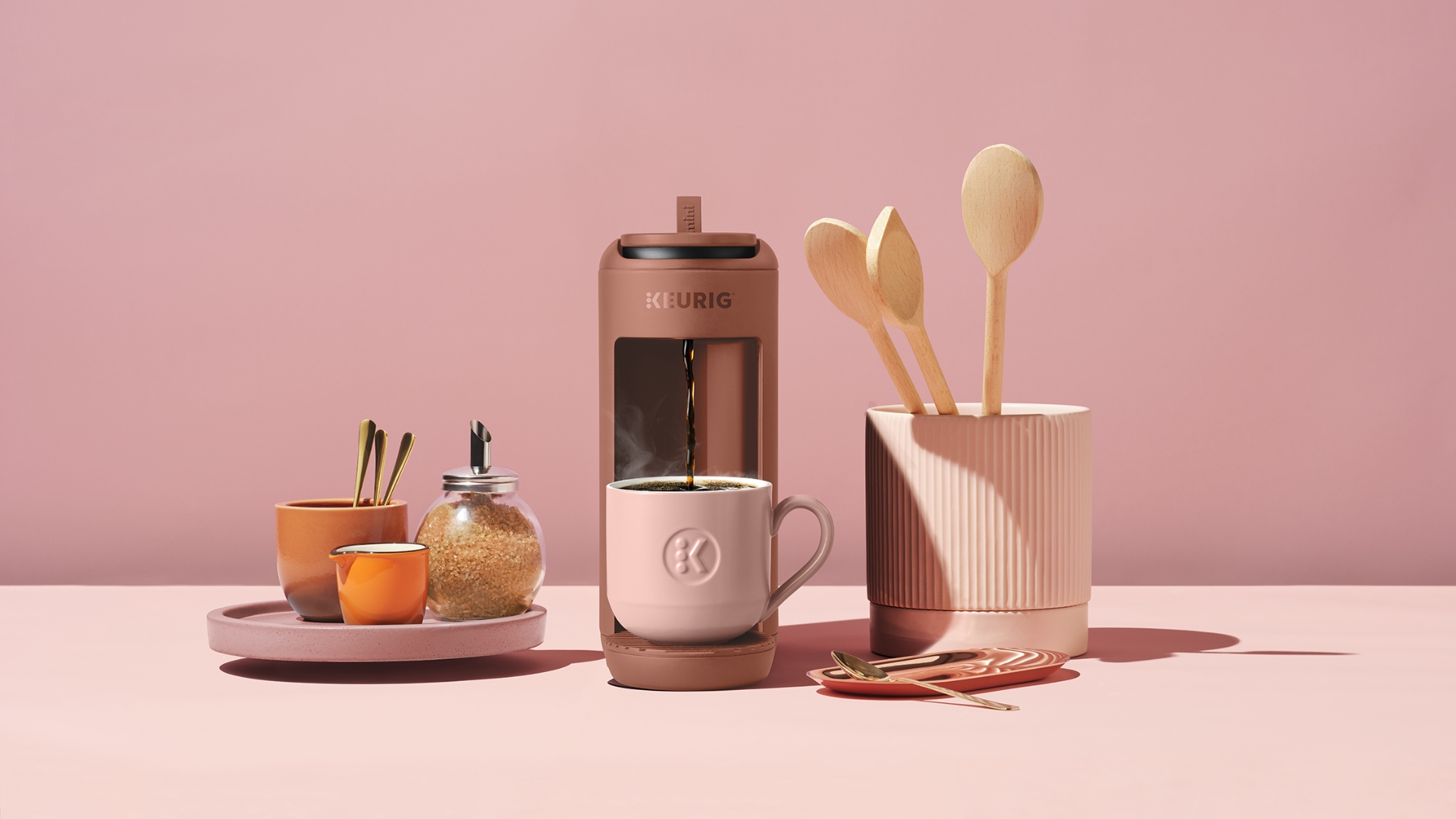 The Keurig K-Mini Mate in Red Rocks with kitchen utensils on the side