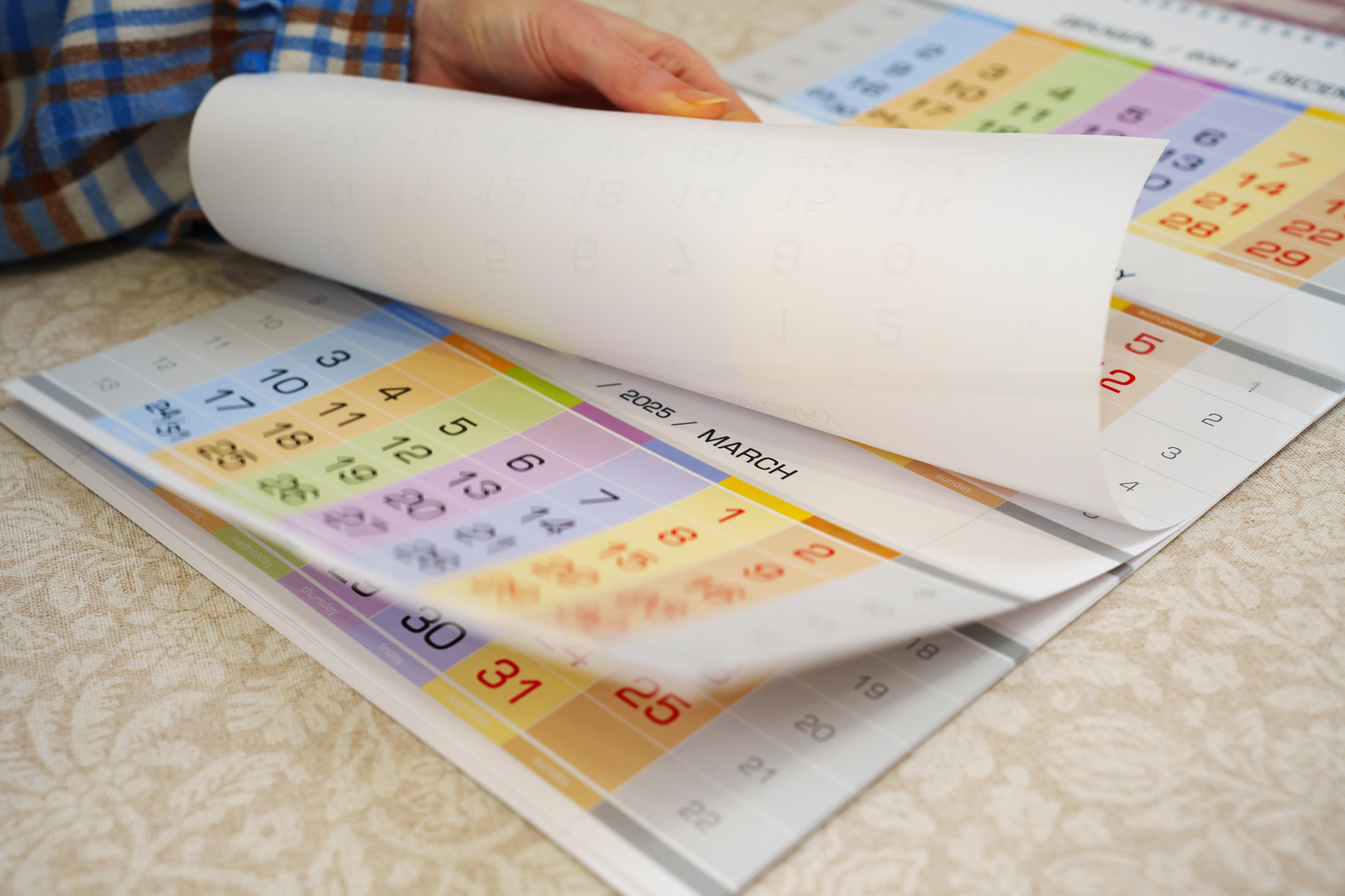 hand is turning the pages of a tear-off wall calendar. Printing calendars with photos as a gift. the rapidity of the passage of time. anticipation of a holiday, event or meeting.