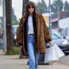 Dakota Johnson wears vintage Levi jeans, leopard coat, white t-shirt and oval sunglasses while shopping in LA.