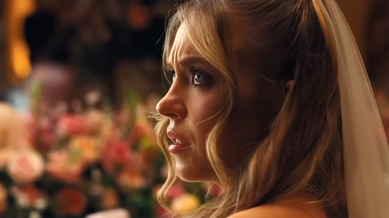 Sydney Sweeney looks off in the distance while sitting at a table covered in flowers at Cassie's Euphoria wedding.