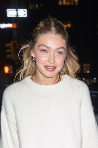 Gigi Hadid wearing a white sweater with her blonde hair pulled back.