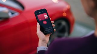 Over the shoulder view of young Asian woman using an app on her smartphone to unlock her smart car