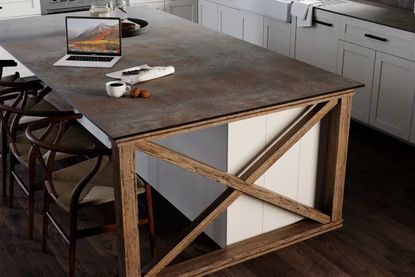 A solid wood table worktop with a laptop and cup of coffee on top.
