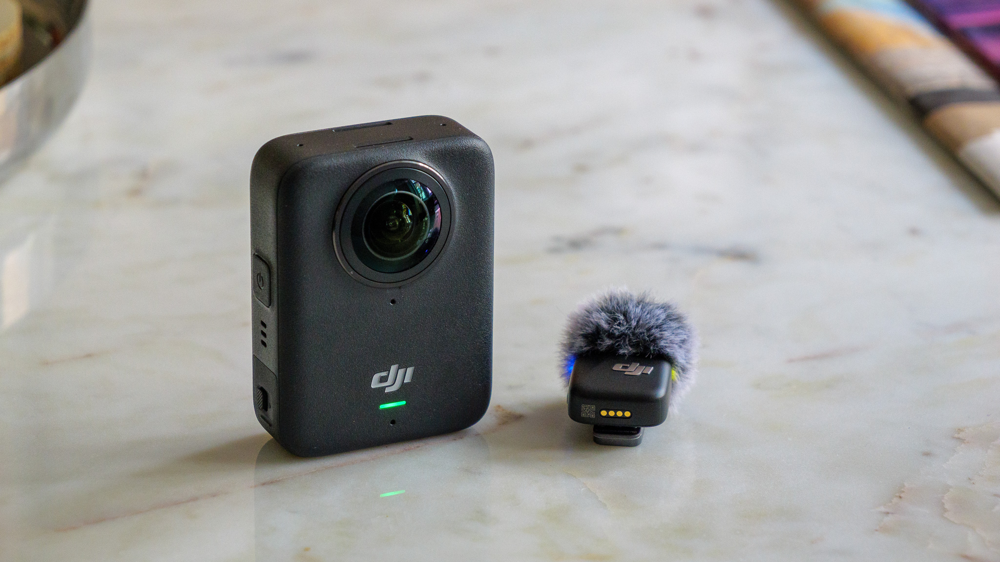 DJI Osmo 360 camera next to DJI Mic Mini on marble table