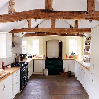 white kitchen with wooden beams on ceiling and lights on it