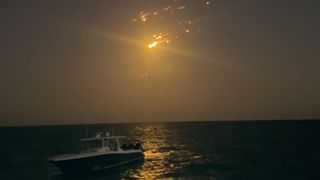 debris from spacex starship falling over a boat in the ocean