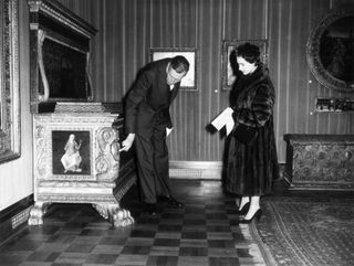 Sir Anthony Blunt shows Princess Margaret a piece of furniture in 1958