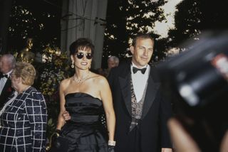 American actor and film director Kevin Costner, wearing a tuxedo and bow tie, and his wife, Cindy Silva, who wears a black off-shoulder outfit and sunglasses, attend the 64th Academy Awards, held at the Dorothy Chandler Pavilion, Los Angeles Music Center in Los Angeles, California, 30th March 1992.