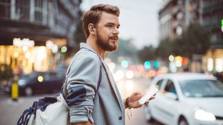 A man wearing a pair of EAH-AZ60 and holding his phone.