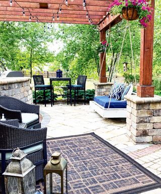 a painted outdoor rug in a patio area with patio seating and a double outdoor swing