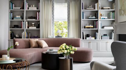 living room with pink curved sofa and gray alcove shelves