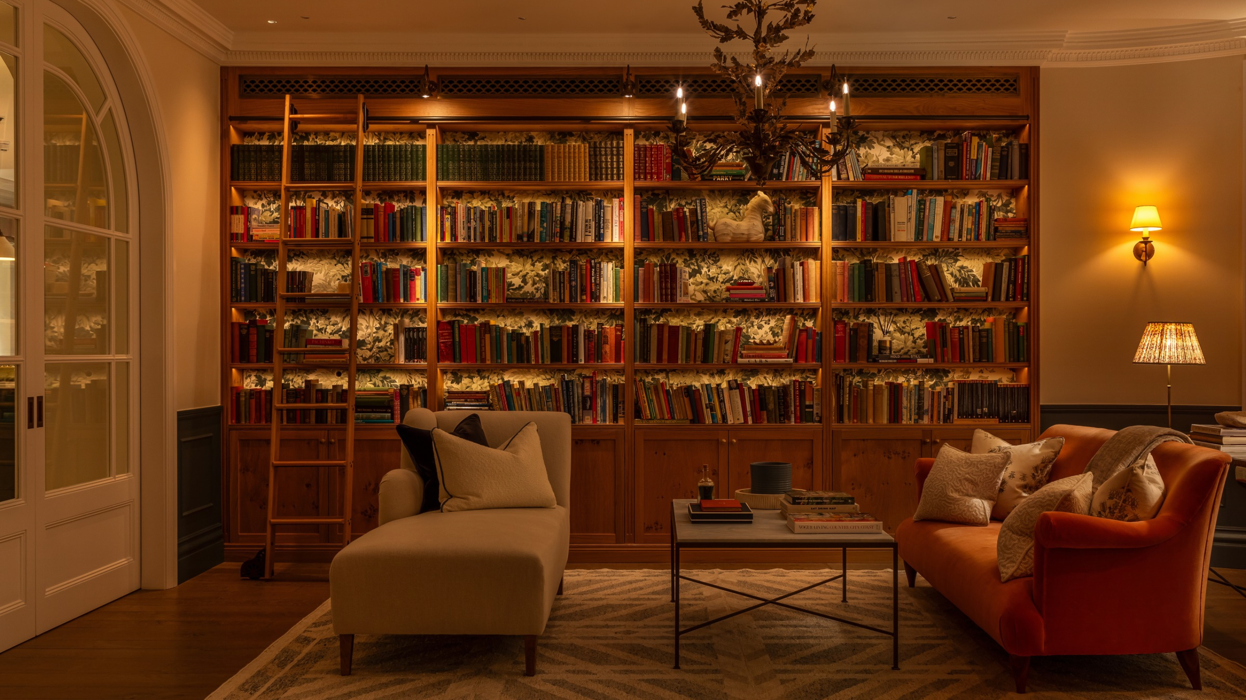 a beautiful sitting room with soft, warm lighting, and a built-in bookshelf with a ladder