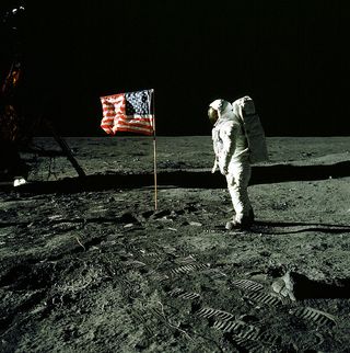 Buzz Aldrin posed for this picture next to the U.S. flag. The rod to hold the flag out horizontally would not extend fully, so the flag ended up with a slight waviness, giving the appearance of being windblown. The flag itself was difficult to erect, it was very hard to penetrate beyond about 6 to 8 inches into the lunar soil.