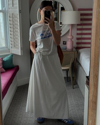 Francesca Saffari wears a vintage t-shirt, long, white skirt and sambas in a selfie.