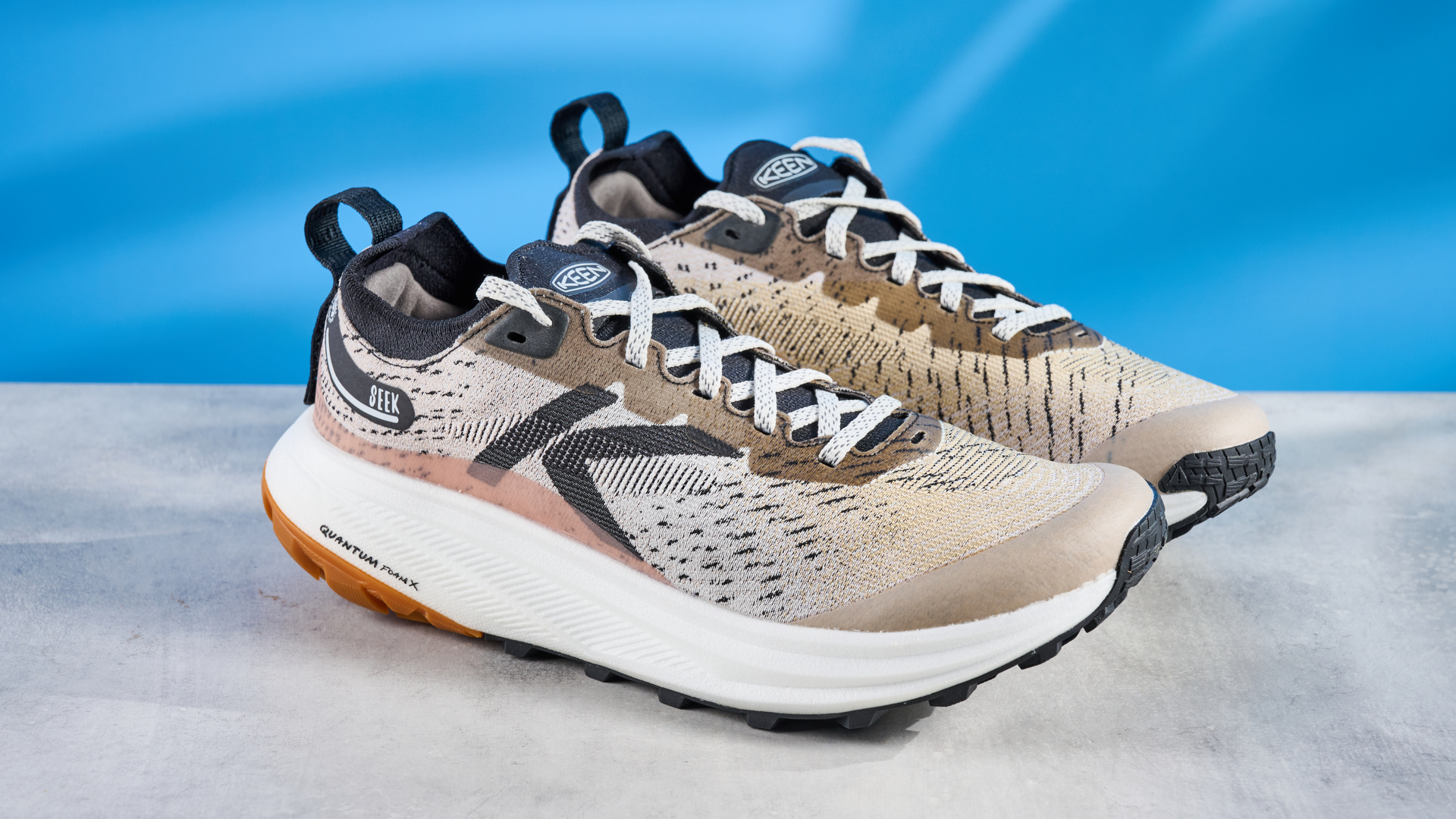 the keen seek trail shoes in brown, black, and beige photographed against the blue tom's guide background