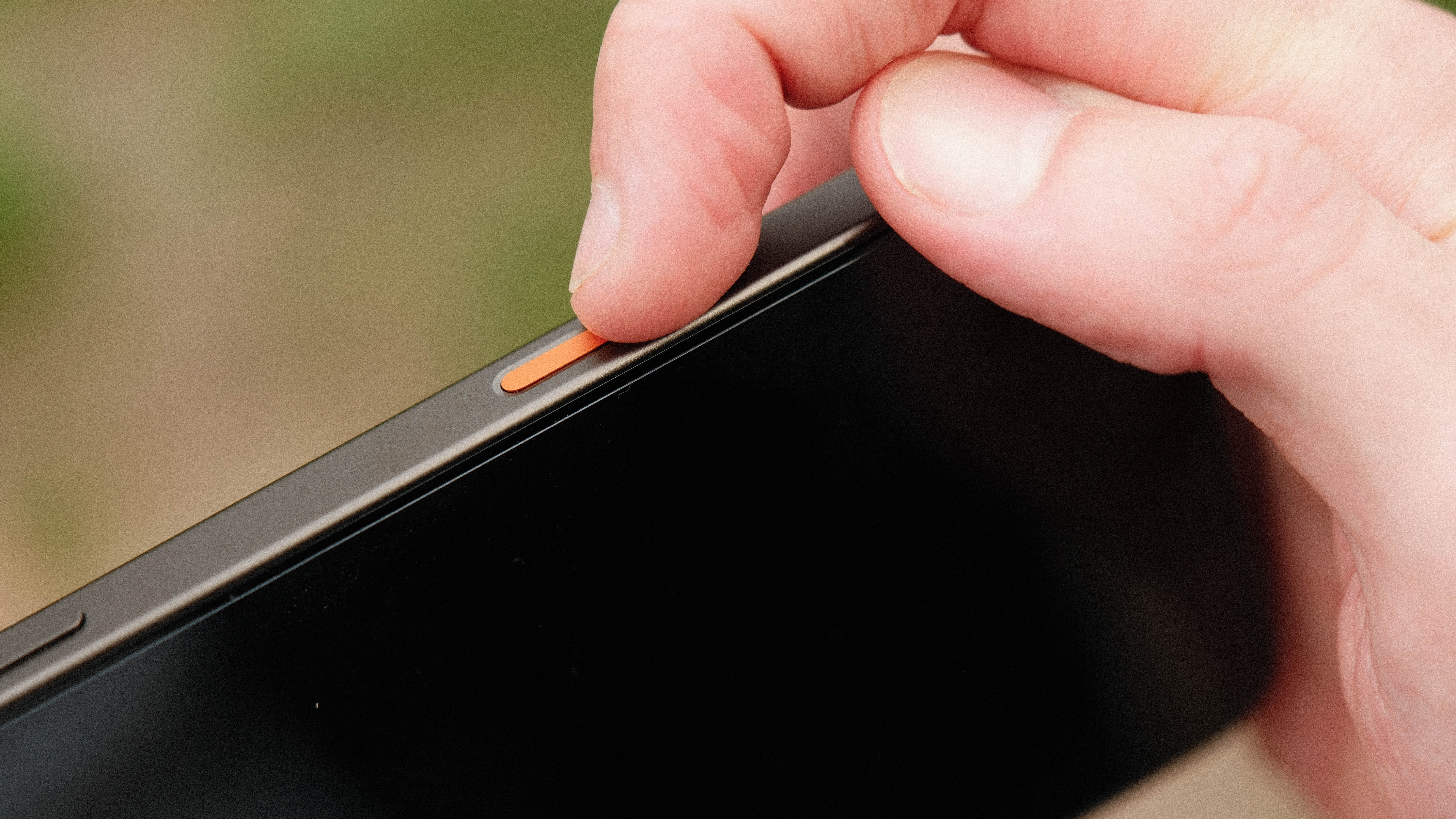 Finger pressing the orange shortcut button on Oppo Find X9 Ultra