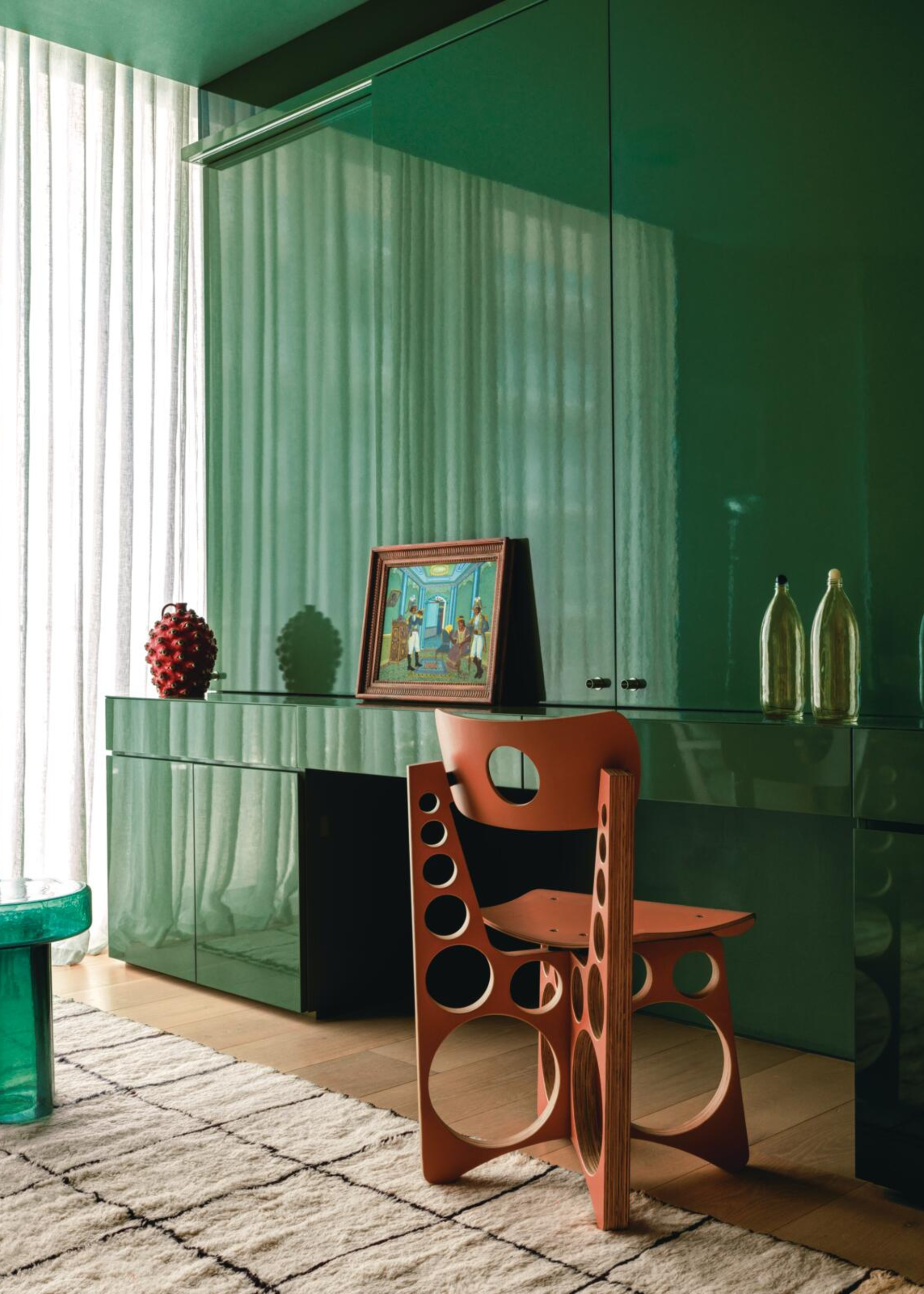 a gloss green storage bedroom configuration with circular modern chair and decor details and sheer cream curtains