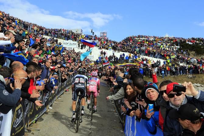 Riders pass heaving throngs of fans