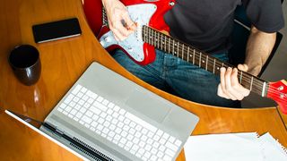 Man records his red guitar with a budget laptop