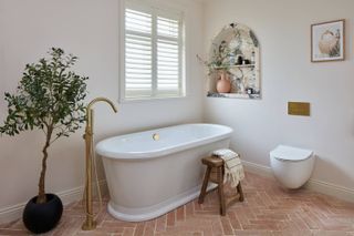 white bathroom with freestanding tub and brick floor