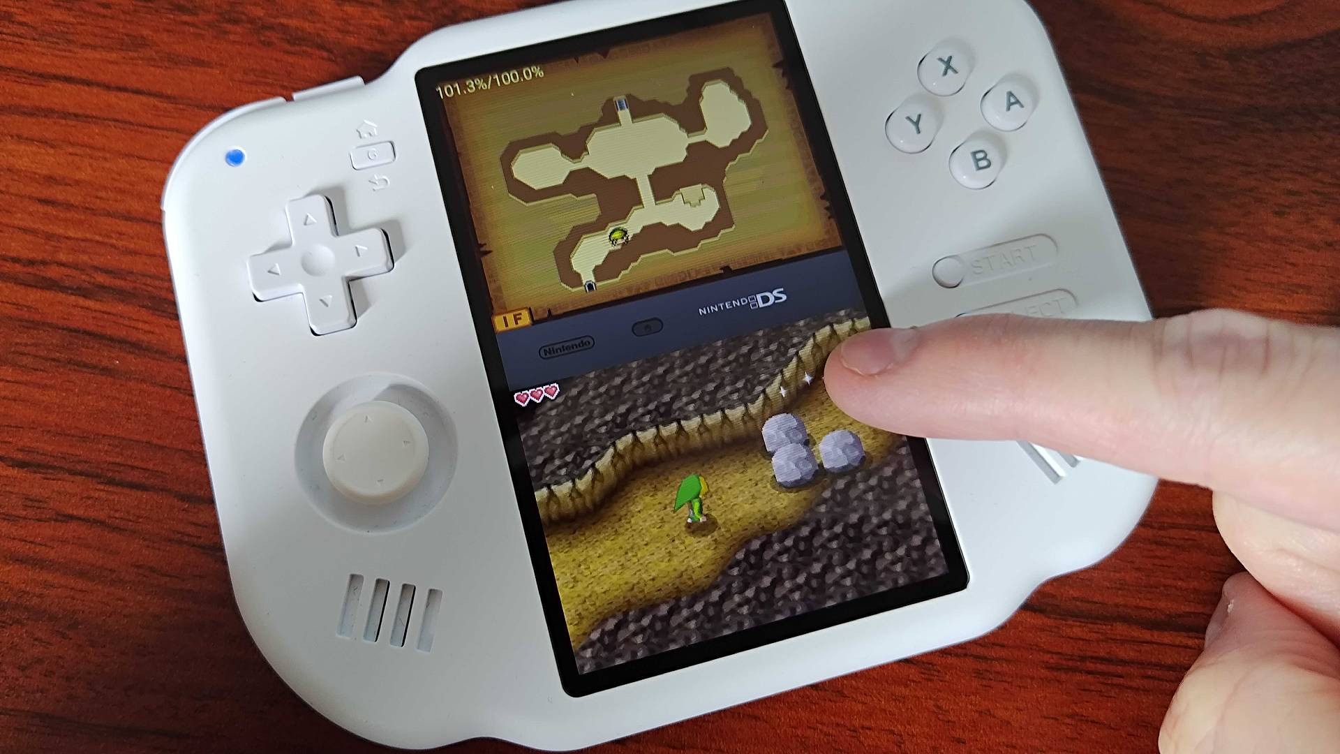 Finger using MagicX Zero 40 touchscreen to play Zelda: Phantom Hourglass on woodgrain desk.