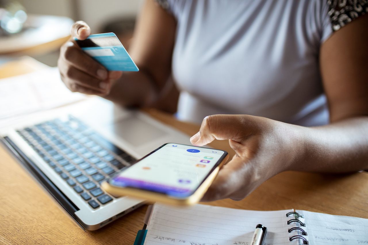 woman looking at her phone holding her card