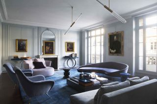 A living room with walls in grey undertones and deep blue sofas
