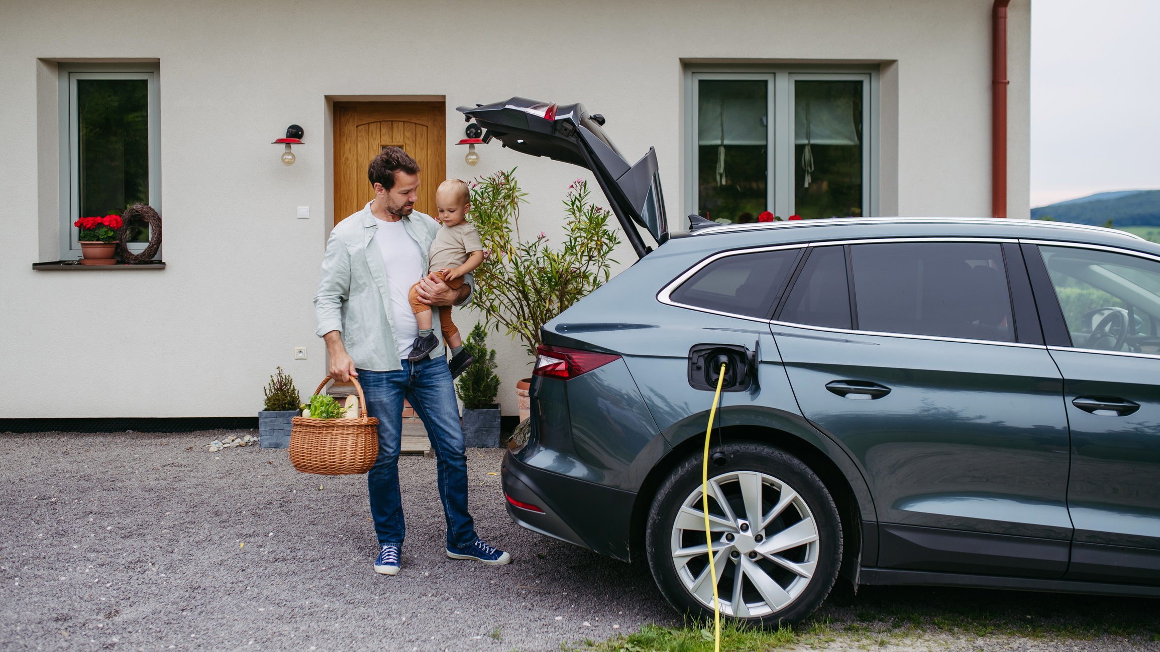 a man holding his baby while his EV charges