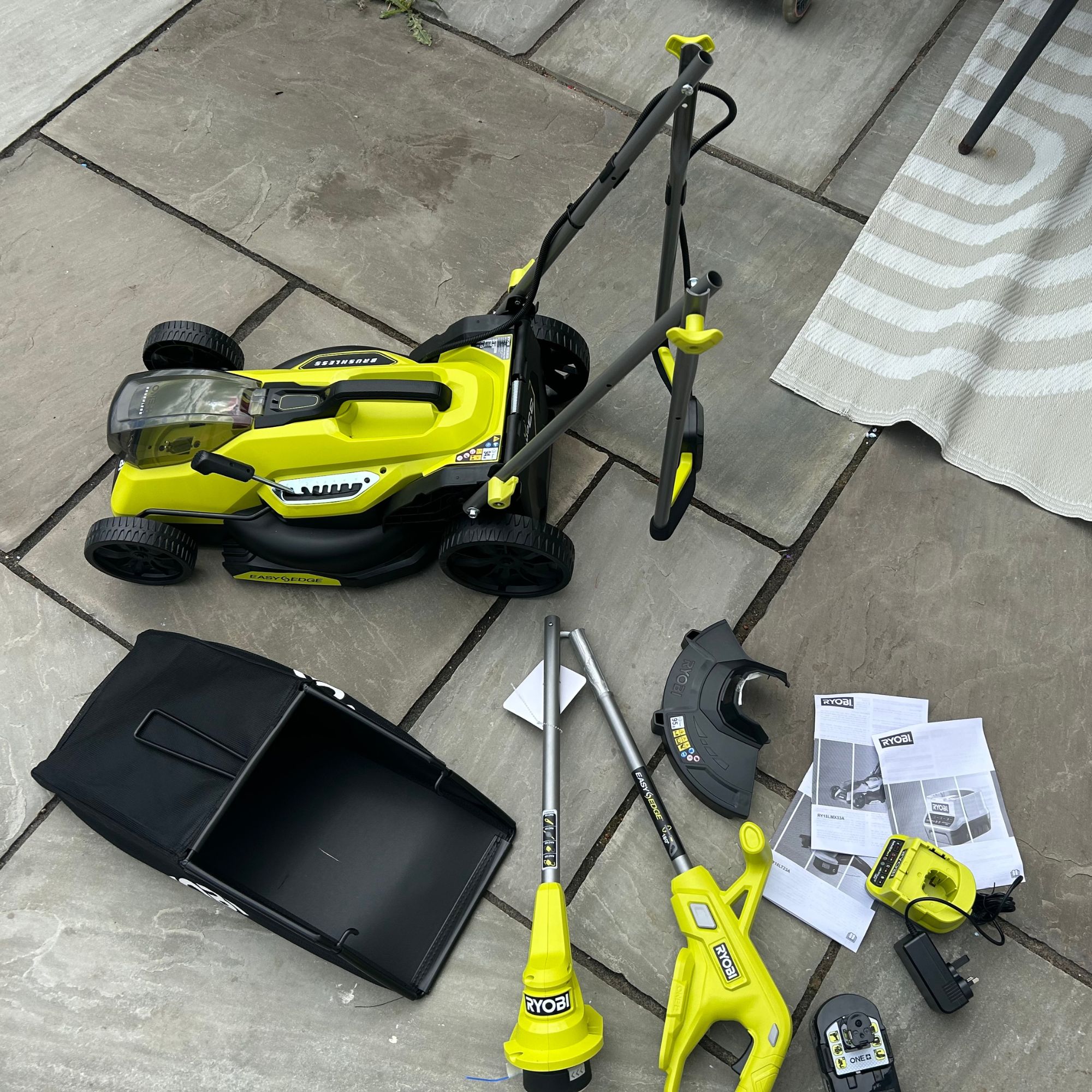 Ryobi lawn mower and strimmer parts on floor in garden