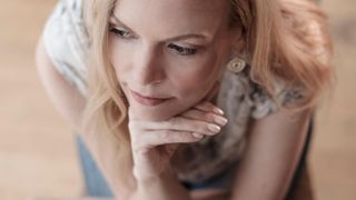 Woman sitting on a chair with her hand on her chin thinking about something