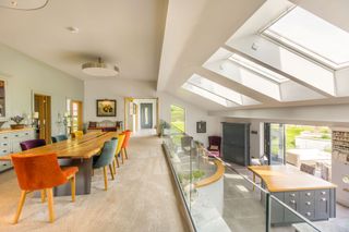 A raised dining area with glass balustrade overlooking the living area of the eco home
