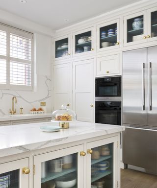 A white kitchen with an island and kitchen cupboard storage ideas that reach to the ceiling