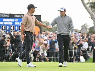 Patrick Cantlay and Xander Schauffele fist bumping on the green
