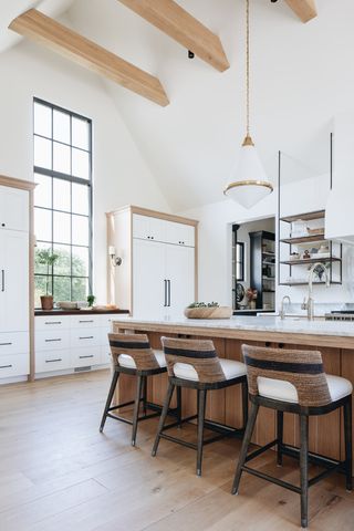 modern white kitchen with exposed ceiling beams and bar stools