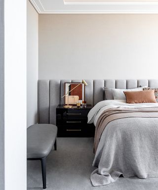 gray bedroom with oversized upholstered headboard and gray leather bench