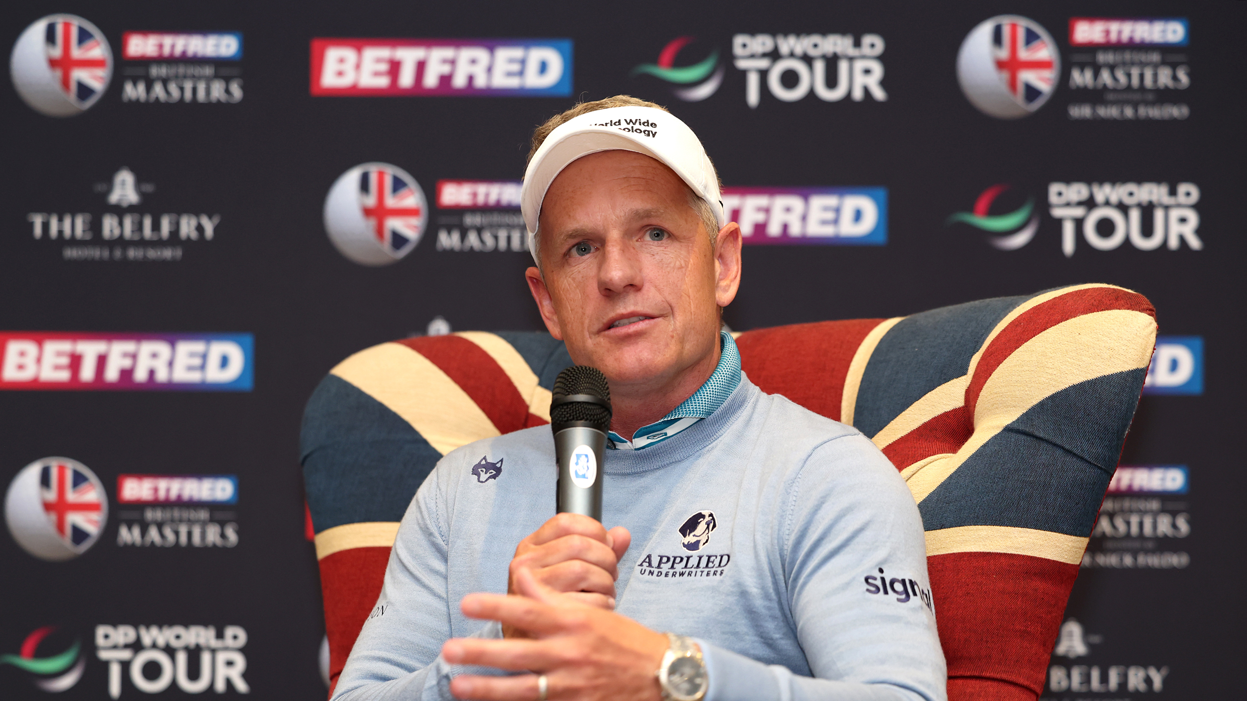 Luke Donald speaks into a microphone while sitting on a Union Jack-pattern chair at the 2025 British Masters