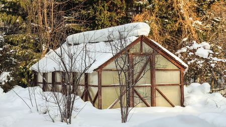 Snow covered greenhouse in the vegetable garden in winter close-up