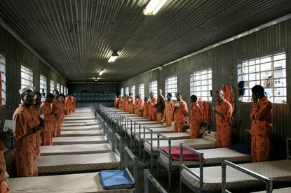 Inside of prison sleeping quarters with prisoners wearing orange jumpsuits
