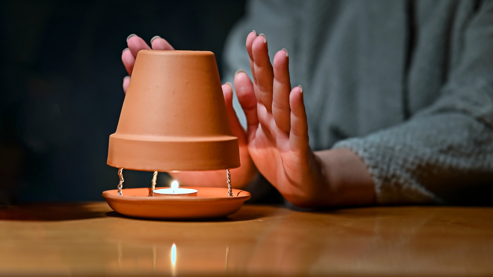 woman warming hands in front of clay pot heater