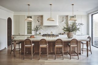 a kitchen with a wooden island, white cabinetry and white zellige tiles on the wall.