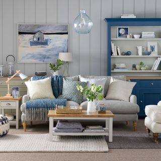 Blue and grey living room with grey tongue and groove wall panelling and a grey sofa