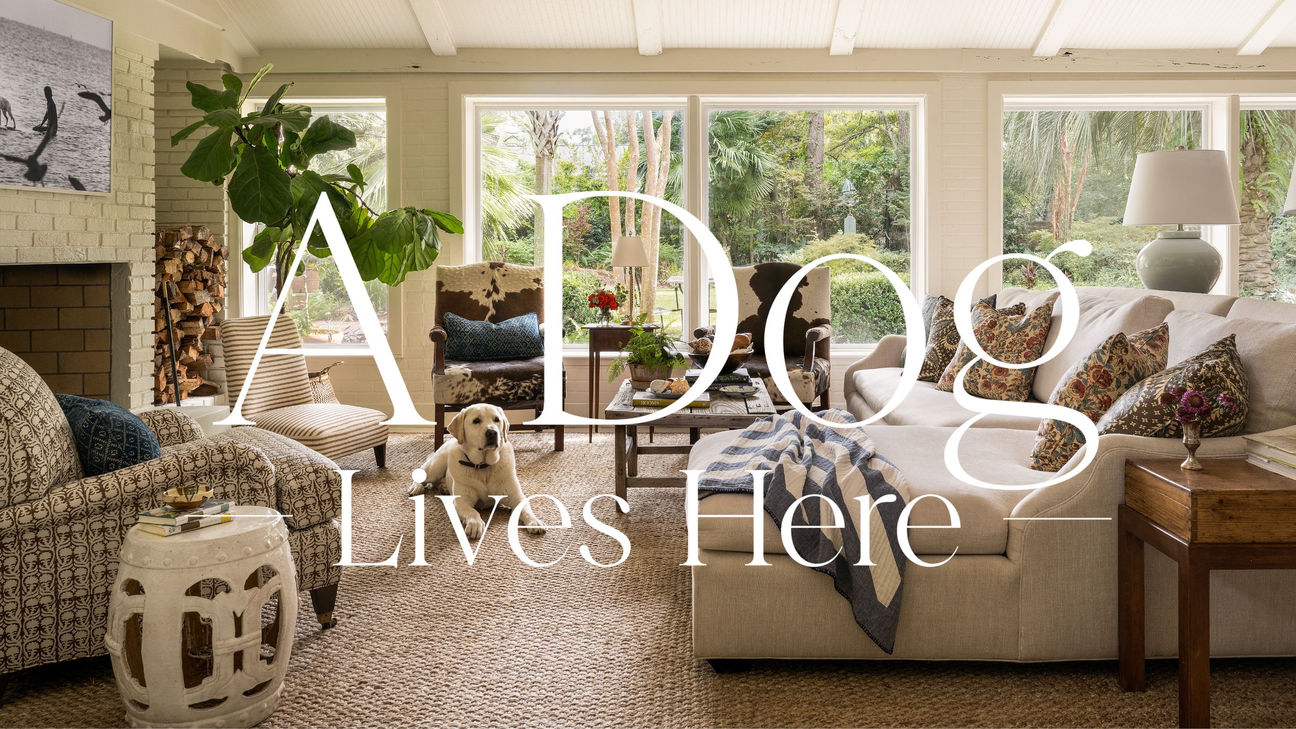 a bright sunroom with sloped celing, stone fireplace, sectional sofa and woven rug with a labrador dog lying on the rug