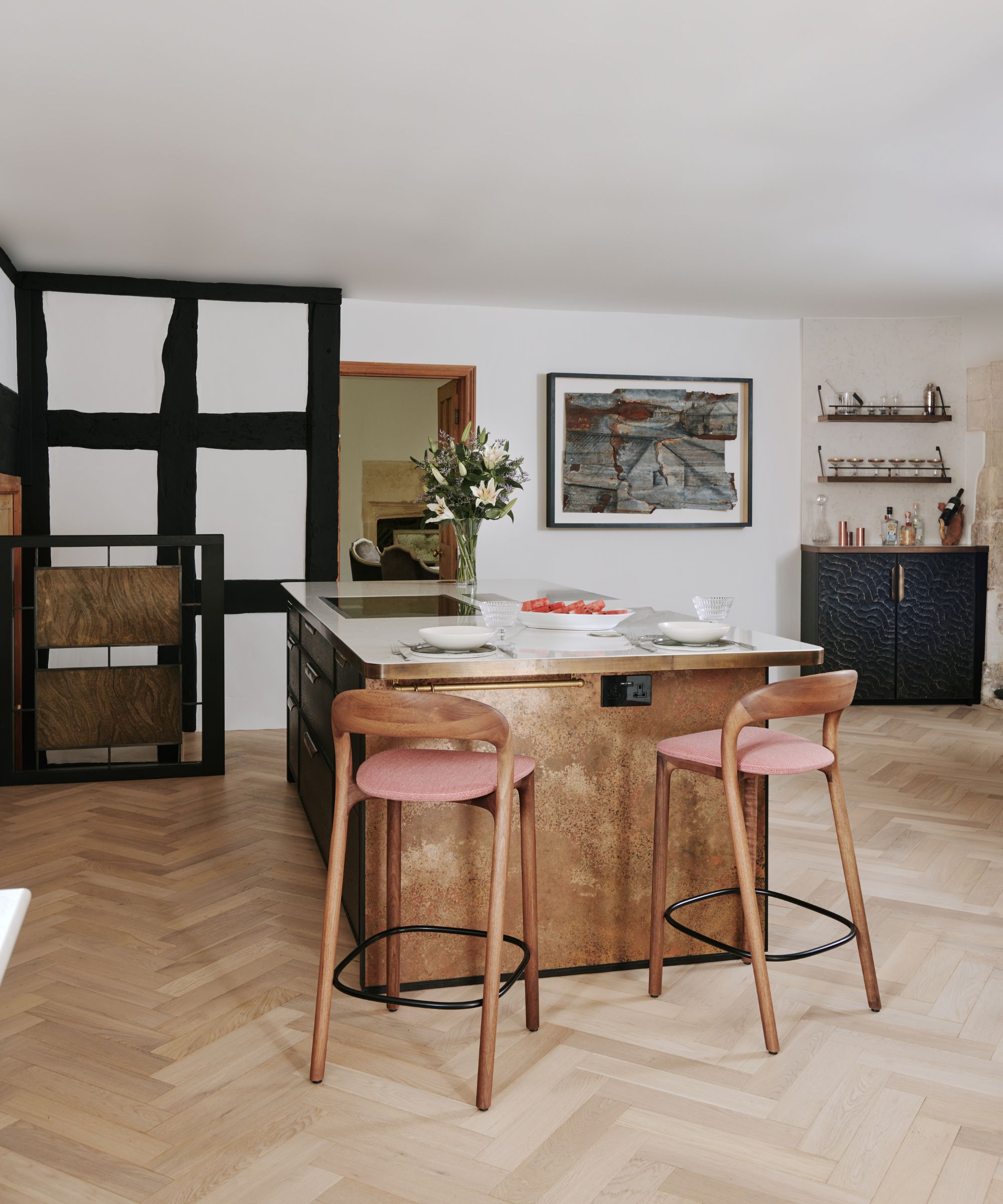 A metallic kitchen island is the focal point of the room with chairs and artwork surrounding