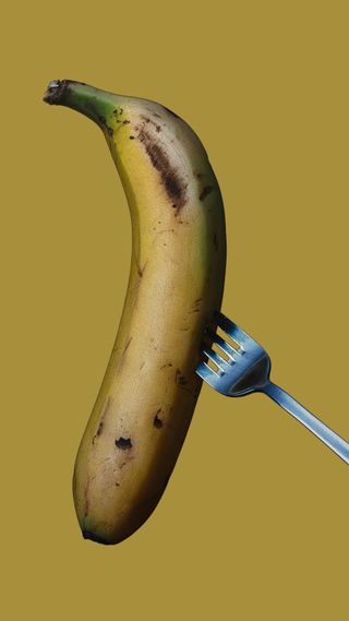 Princess Anne's bizarre breakfast, ripe banana on a fork on a yellow background