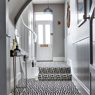 a white hallway and front door with bold monochrome patterned carpet