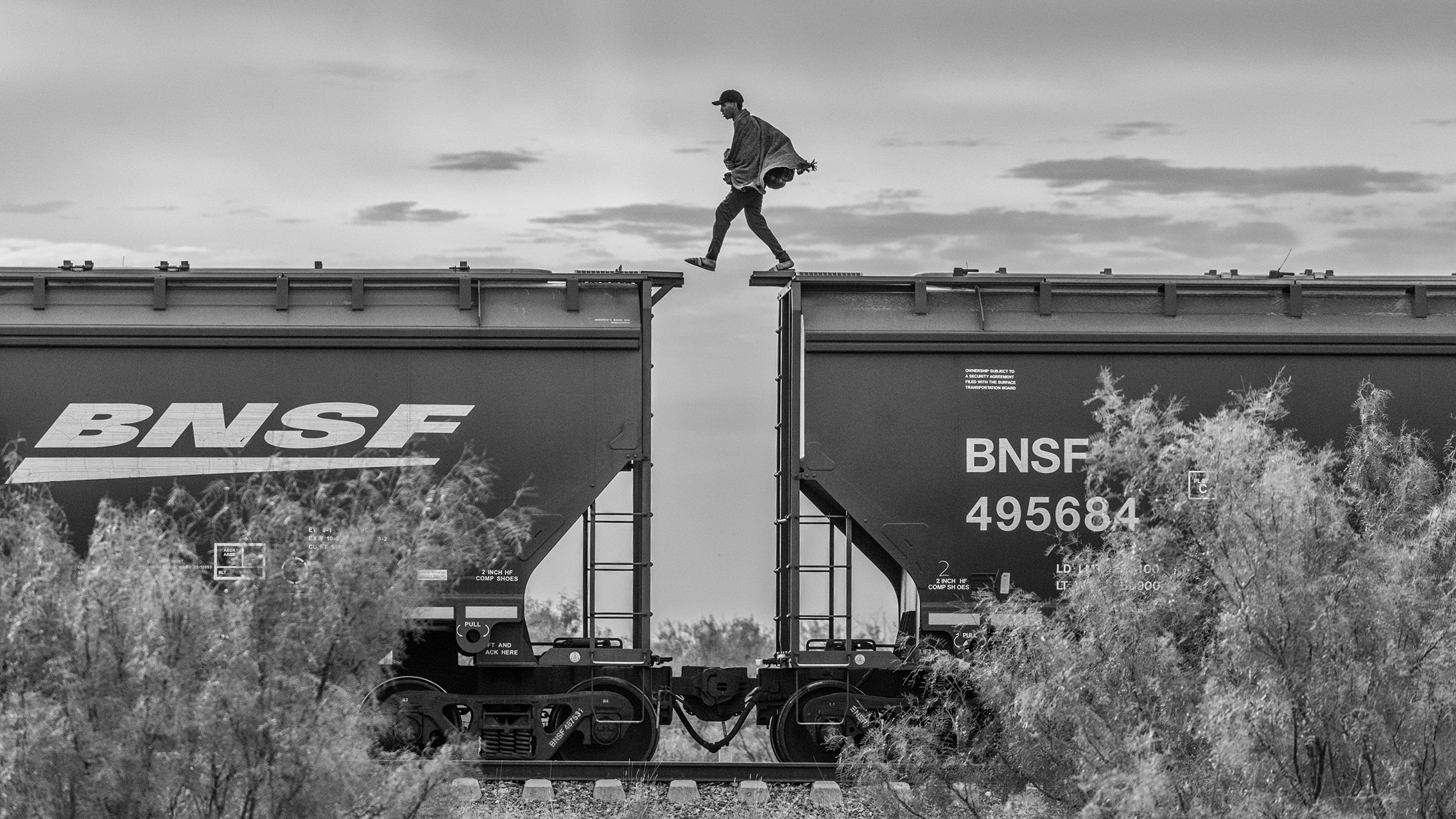 A migrant walks on top of a parked freight train knownas “The Beast” on the outskirts of Piedras Negras, Mexico 2023. From the series “The Two Walls”