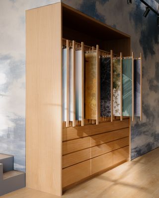 A wooden cabinet with vertical drawers showing wallpaper samples by Calico